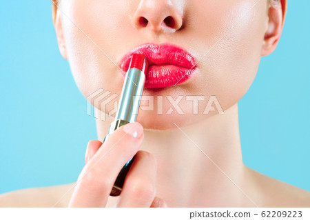 Beautiful woman paints lips with lipstick. Beautiful woman face. Makeup detail. Beauty girl with perfect skin. Red lips and health skin. The concept of beauty, glamor and passion Beautiful woman paints lips with lipstick. Beautiful woman face. Makeup detail. Beauty girl with perfect skin. Red lips and health skin. The concept of beauty, glamor and passion 62209223