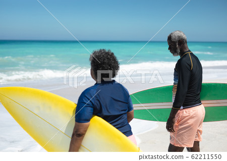 Old couple with surfboard at the beach 62211550