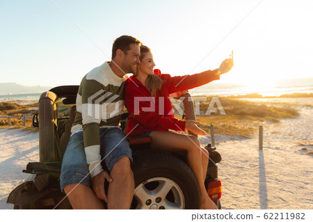 Couple taking photos on a car Couple taking photos on a car 62211982