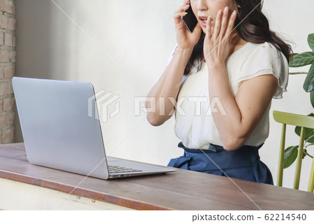 在電話期間看計算機的驚訝的女人 62214540