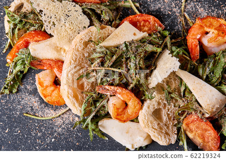 Delicious dish with grilled shrimps, squid, croutons and arugula salad and spicy fried prawns. Restaurant menu, natural and organic food concept. 62219324