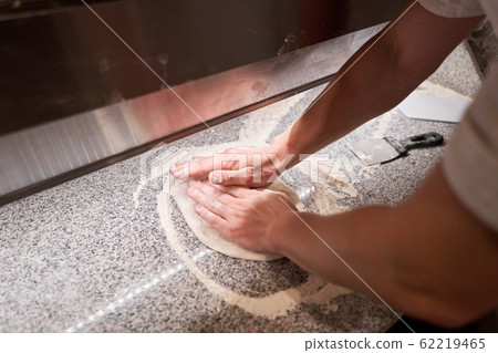 Dough for Neapolitan pizza, the chef rolls out the blanks. Closeup hand of chef baker in uniform white apron cook pizza at kitchen 62219465