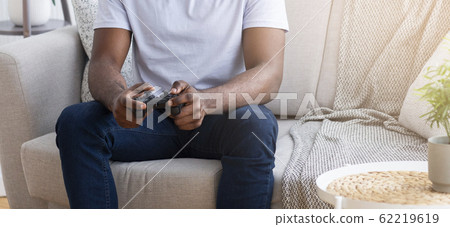 African guy playing video games with joystick at home 62219619