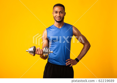 African bodybuilder pumping up biceps with dumbbells 62219689