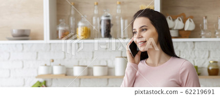 Young woman talking on cellphone at kitchen interior 62219691