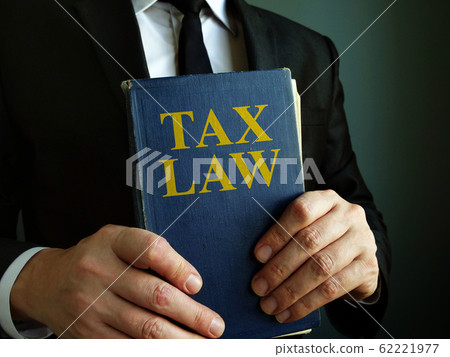 Accountant holds tax law book. Accountant holds tax law book. 62221977
