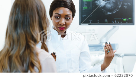 Gynecologist showing woman early ultrasounds of her pregnancy 62222870