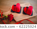 Two heart-shaped desserts on a wooden board with a red rose. 62225024