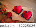Two heart desserts on a wooden board with a red rose and a red ribbon. 62225026