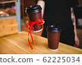 A woman holds a plastic glass of coffee into the camera 62225034