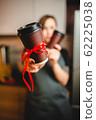 A woman holds a plastic glass of coffee into the camera 62225038