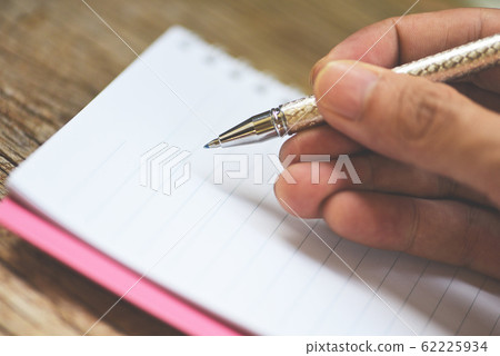 Holding a pen on sketch book or notebook blank Holding a pen on sketch book or notebook blank 62225934