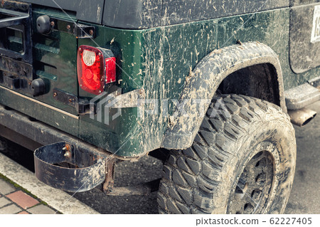 Close-up detail mud dirty wheel of off-road lifted awd ATV SUV car after extreme rally cross competition. Tuned all-terreain-vehicle part outdoor swamp countryside trophy challenge. Adventure concept 62227405