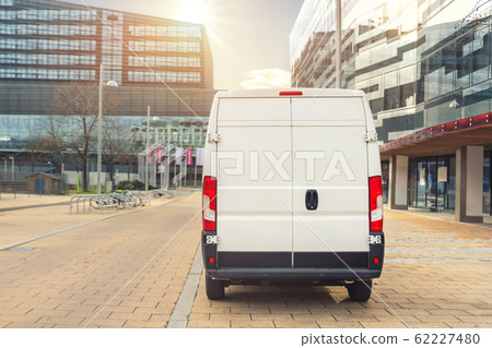 Unrecognizable altered delivery van in european city central . Medium lorry minivan courier vehicle deliver package at residential office building in downtown area. Commercial shipping logistics 62227480