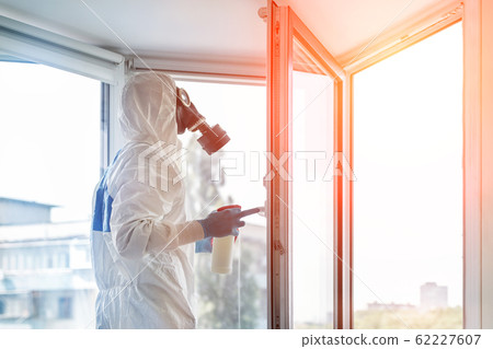 Man wearing protective biological suit and gas-mask due to mers coronavirus global pandemic warning and danger. Medic sphysician scientist make disinfection and ventilation at hospital clinic room 62227607