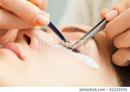 Woman with long eyelashes in a beauty salon during eyelash extension 62228559