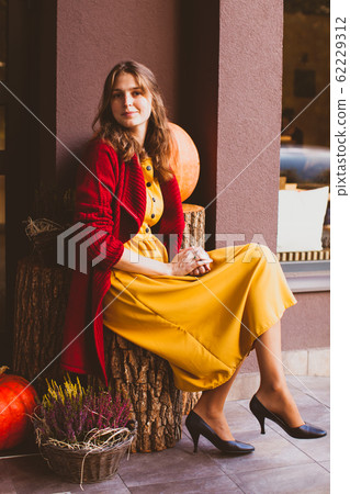 Stylish woman designer sitting in front of gardening centre. Autumn design outside. Stylish woman designer sitting in front of gardening centre. Autumn design outside. 62229312