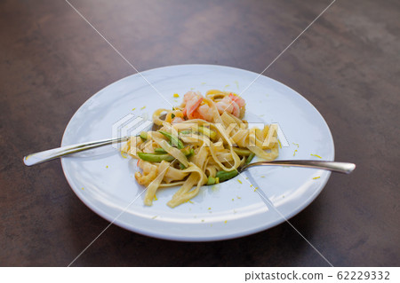 Close up of a plate of pasta topped with shrimp 62229332