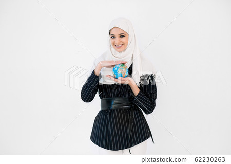 Pretty smiling young Arabic woman in hijab holding Earth globe planet in hands against white background. Earth day holiday concept. 62230263