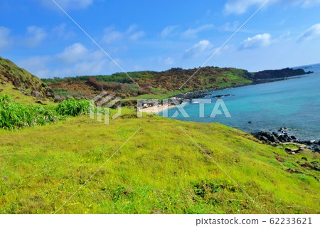 A corner of the island with green grass, blue water and sky A corner of the island with green grass, blue water and sky 62233621