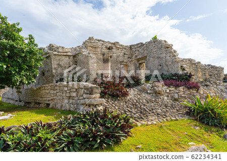 Ruins of ancient Tulum. Architecture of ancient maya. View with temple and other old buildings, houses. Blue sky and lush greenery of nature. travel photo. Wallpaper or background. Yucatan.  62234341