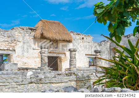 Ruins of ancient Tulum. Architecture of ancient maya. View with temple and other old buildings, houses. Blue sky and lush greenery of nature. travel photo. Wallpaper or background. Yucatan. Ruins of ancient Tulum. Architecture of ancient maya. View with temple and other old buildings, houses. Blue sky and lush greenery of nature. travel photo. Wallpaper or background. Yucatan. 62234342