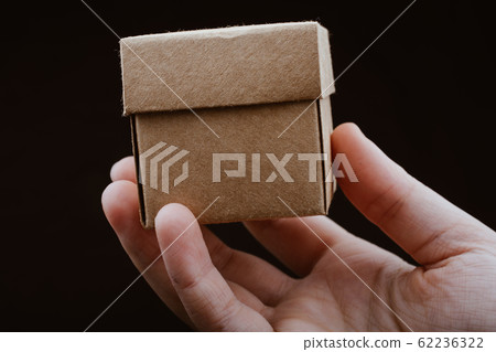 Hand holding cardboard box on a black background 62236322