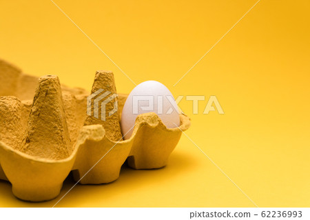 one egg inside of a six pack cardboard on yellow background. concept designs one egg inside of a six pack cardboard on yellow background. concept designs 62236993