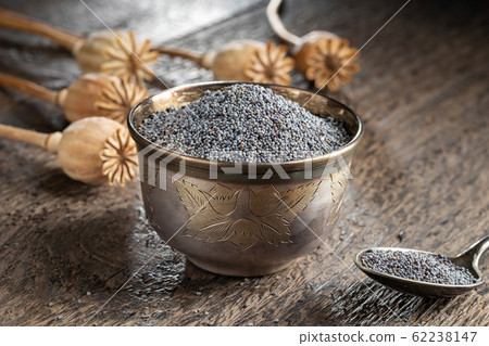 Poppy seeds in a cup with poppy pods in the background 62238147