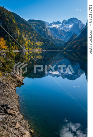 Peaceful autumn Alps mountain lake with clear transparent water and reflections. Gosauseen or Vorderer Gosausee lake, Upper Austria. Dachstein summit and glacier in far. Peaceful autumn Alps mountain lake with clear transparent water and reflections. Gosauseen or Vorderer Gosausee lake, Upper Austria. Dachstein summit and glacier in far. 62238701