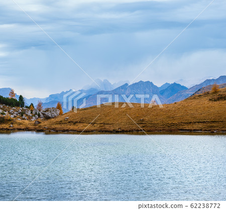 Overcast morning autumn alpine Dolomites mountain scene. Peaceful Valparola Path and Lake view, Belluno, Italy. Overcast morning autumn alpine Dolomites mountain scene. Peaceful Valparola Path and Lake view, Belluno, Italy. 62238772