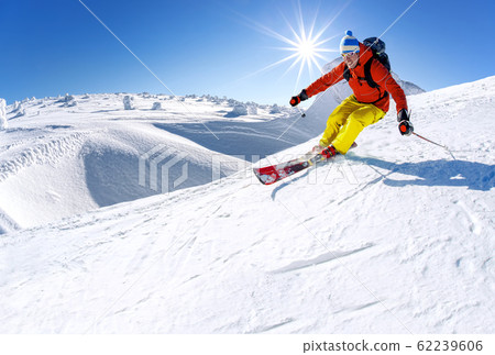 Skier skiing downhill in high mountains against Skier skiing downhill in high mountains against 62239606