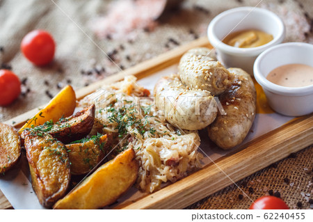 Lunch Time. Sausages potatoes and braised cabbage on board isolated on table creative serving close-up Lunch Time. Sausages potatoes and braised cabbage on board isolated on table creative serving close-up 62240455