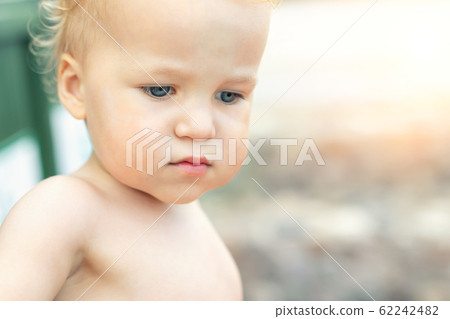 Close-up portrait of cute pensive upset caucasian 2 year old toddler boy portrait standing alone at beach summer day and looking aside. Child with far-away look. Kid thinking of life and future Close-up portrait of cute pensive upset caucasian 2 year old toddler boy portrait standing alone at beach summer day and looking aside. Child with far-away look. Kid thinking of life and future 62242482