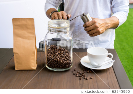 Person grinding coffee with manual coffee grinder 62245990