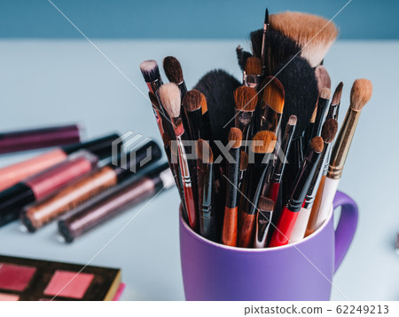 set of professional makeup brushes on the background of a palette with colored eye shadows and cosmetics set of professional makeup brushes on the background of a palette with colored eye shadows and cosmetics 62249213