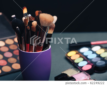 set of professional makeup brushes on the background of a palette with colored eye shadows and cosmetics set of professional makeup brushes on the background of a palette with colored eye shadows and cosmetics 62249222