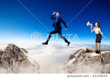Businessman jumping over a cliff and boss is cheering with bullhorn. Businessman jumping over a cliff and boss is cheering with bullhorn. 62249639
