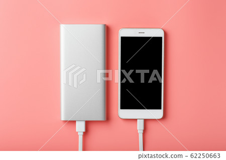 Powerbank charges a smartphone on a pink 62250663