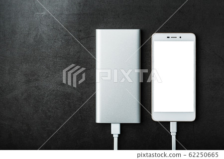 A white Powerbank charges a smartphone on a black A white Powerbank charges a smartphone on a black 62250665