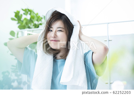A woman wiping her hair with a towel. 62252203
