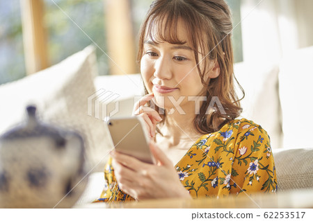 Woman looking at a smartphone in the living room Woman looking at a smartphone in the living room 62253517