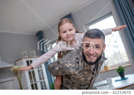 Dad officer and little daughter play airplane at home. Dad officer and little daughter play airplane at home. 62253670