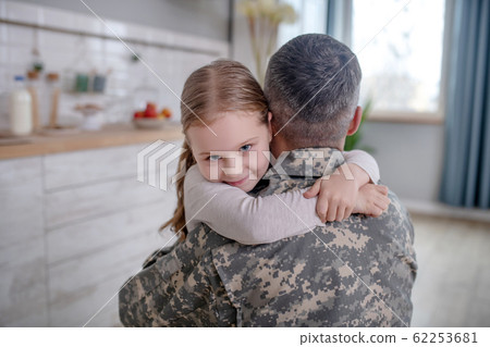 Little girl hugging a mans neck in a uniform. 62253681