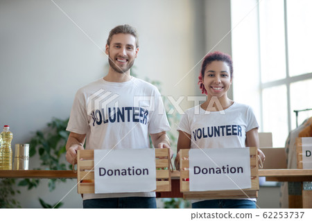 Young volunteers standing with boxes for charity help in their hands. Young volunteers standing with boxes for charity help in their hands. 62253737