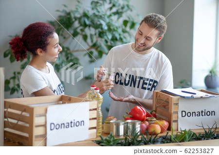 Young man and girl at a charity center packing food. Young man and girl at a charity center packing food. 62253827