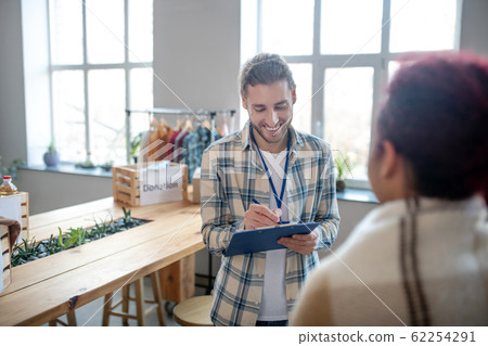 Young man with beard standing writing smiling. 62254291