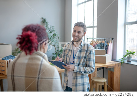 Young smiling man with badge,notepad standing in front of girl. 62254292