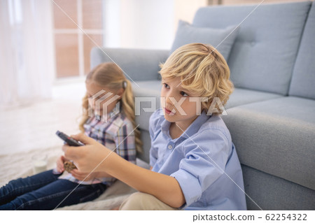 Boy and girl watching tv, boy holding remote control Boy and girl watching tv, boy holding remote control 62254322