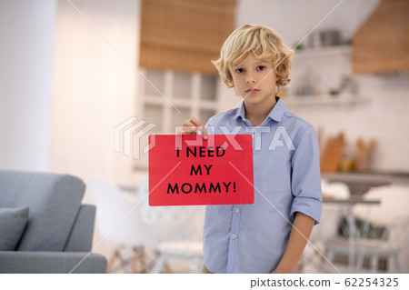 Boy holding sign, feeling upset and missing his mommy 62254325